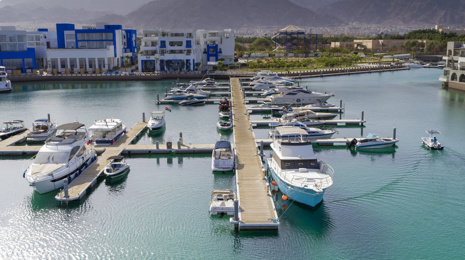 Elevated view of yachts and small boats docked along the waterfront apartments of Ayla Oasis, Aqaba.