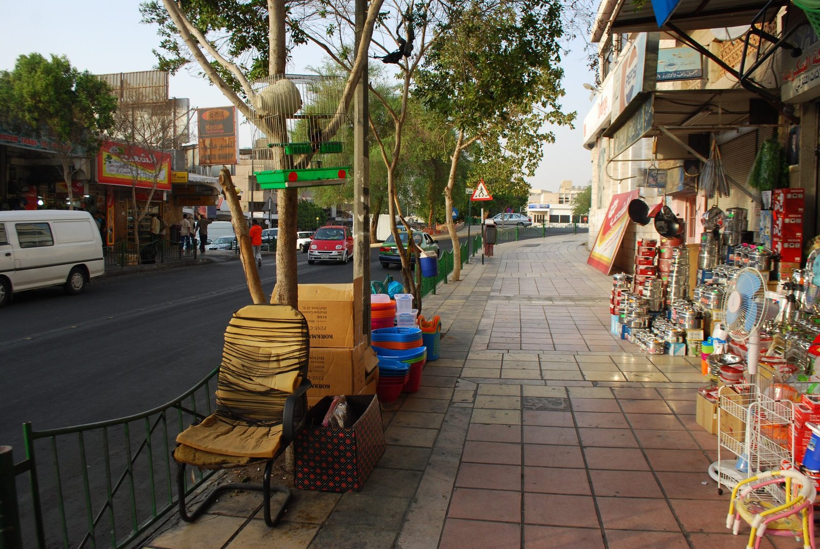 A shaded pavement in the Aqaba shopping quarter, housewares and basketware set out in front of the shops.