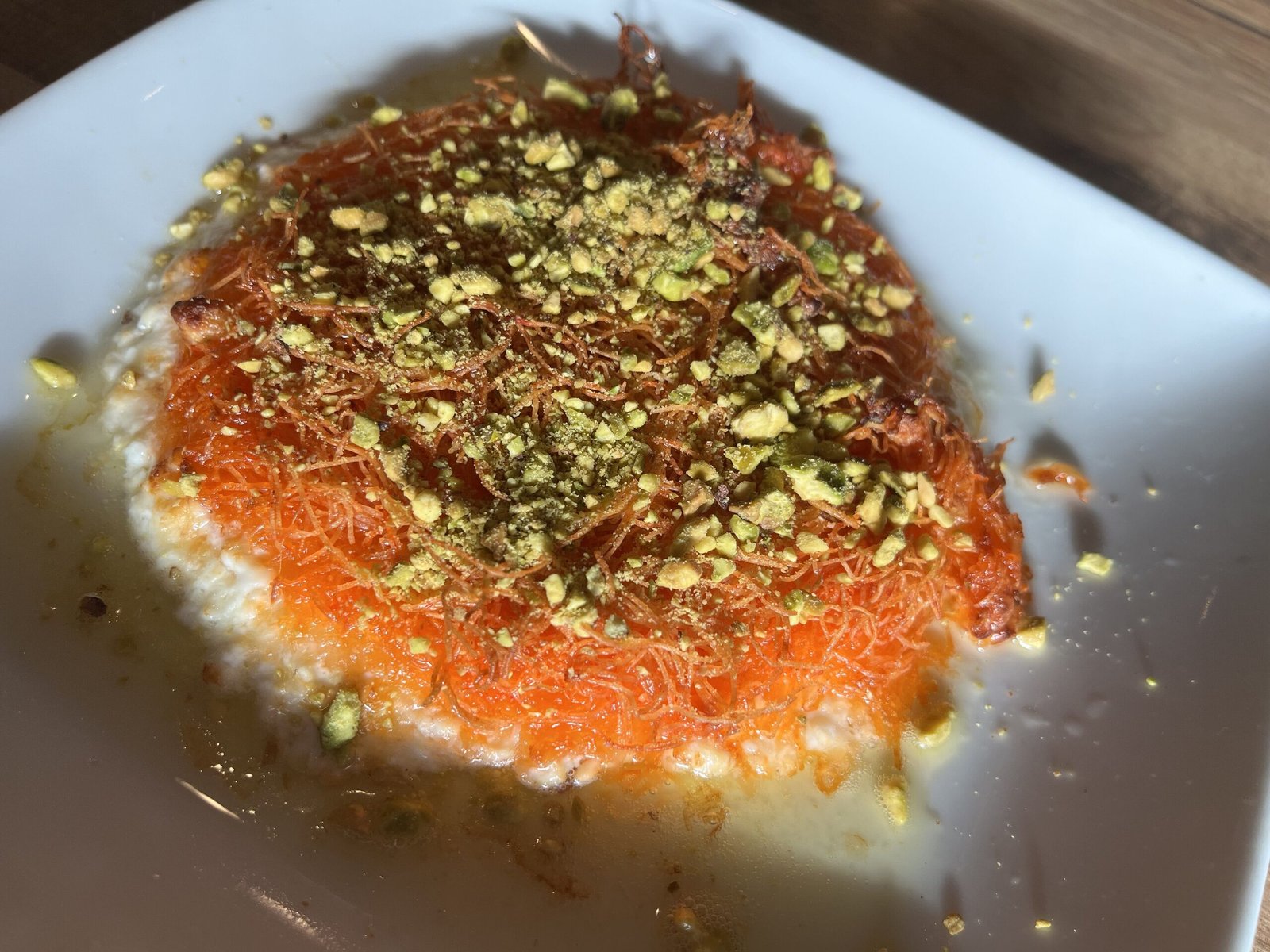 قطعة كنافة خشنة بجبن الغنم الذائب والقطر والفستق المجروش.
