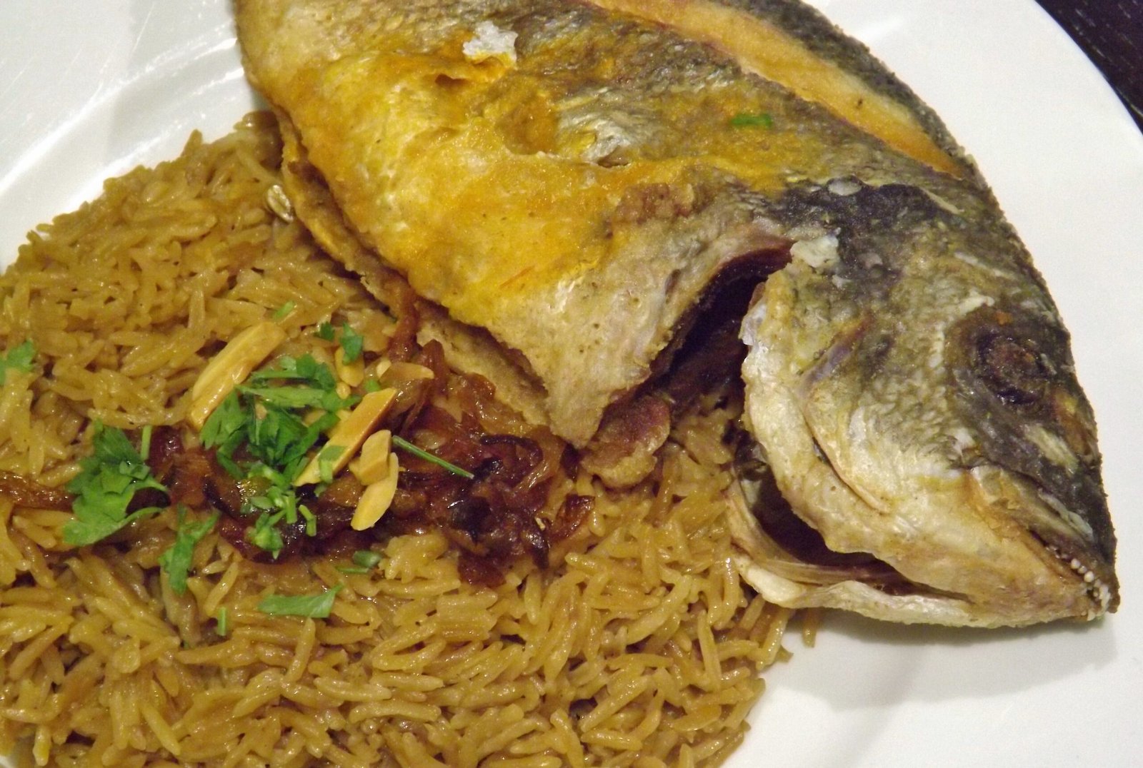 Sayadieh — a whole baked fish served over spiced rice with fried onions.