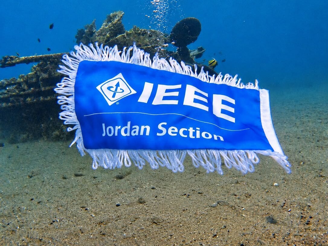 The blue IEEE Jordan Section pennant, fringed in white, hanging in the water in front of the sunken tank.